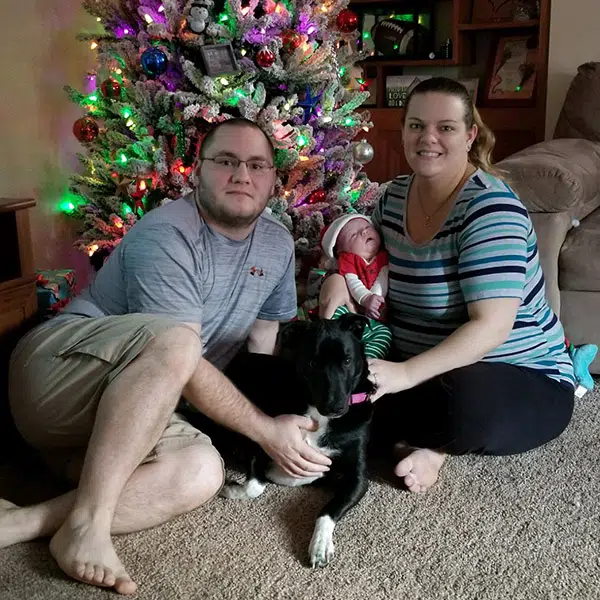 Denise and Jeremiah sit under a christmas tree with their baby